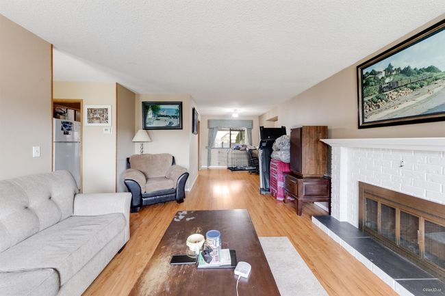 Living area featuring light wood finished floors, a textured ceiling, and a brick fireplace | Image 4