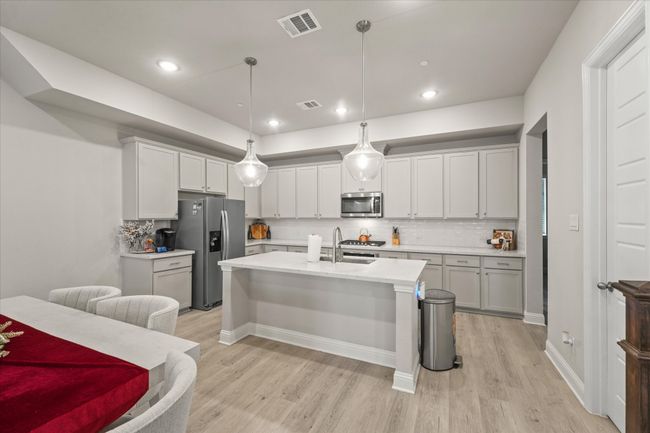 Kitchen with appliances with stainless steel finishes, light wood finished floors, backsplash, hanging light fixtures, and recessed lighting | Image 7