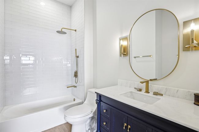 Bathroom featuring bathing tub / shower combination, vanity, and light wood-type flooring | Image 25