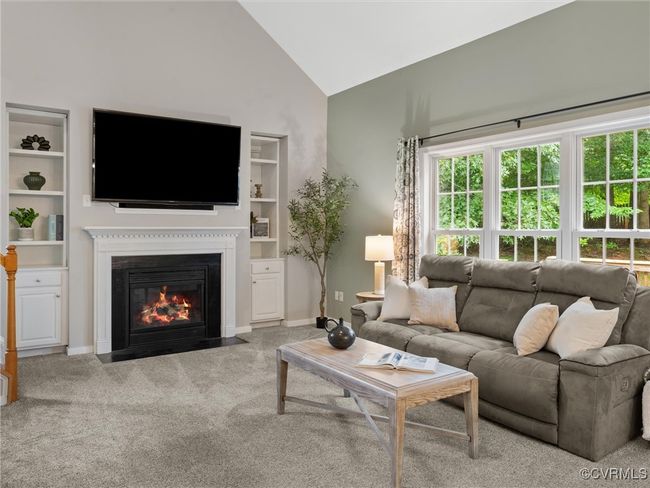 Living room with built in features, carpet floors, a fireplace with flush hearth, and high vaulted ceiling | Image 9