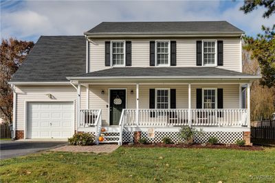 View of front facade with a garage, a porch, and a front lawn | Image 1