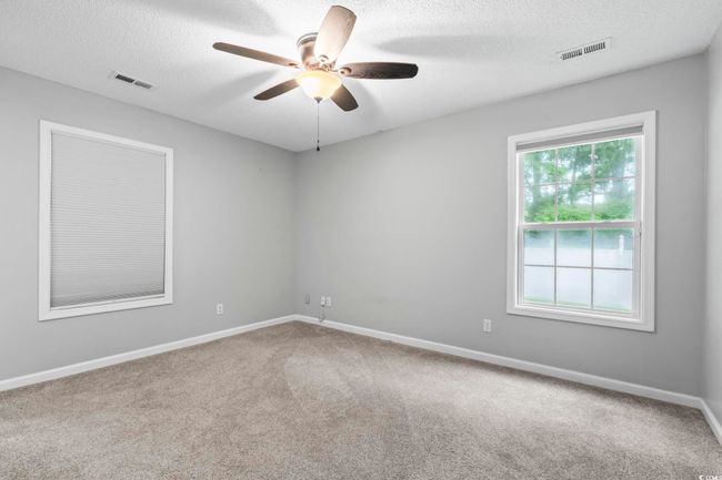 Carpeted empty room with ceiling fan and a textured ceiling | Image 21