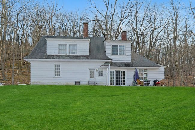 Rear view of property with a lawn, a chimney, and roof with shingles | Image 46