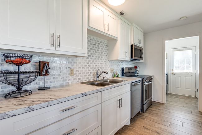 Kitchen with stainless steel appliances, white cabinets, and backsplash | Image 12