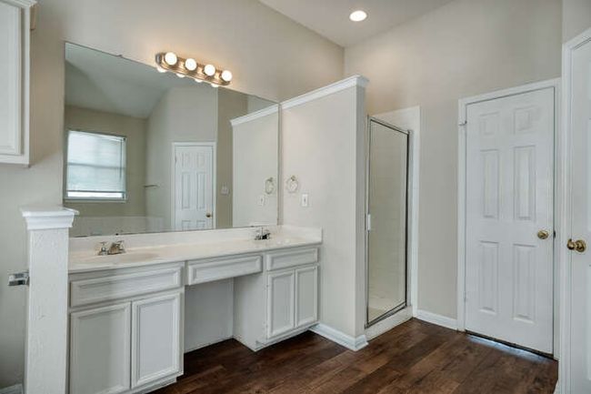 Bathroom with double vanity, wood finished floors, a stall shower, and baseboards | Image 6