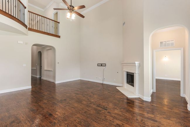 Unfurnished living room featuring high vaulted ceiling, arched walkways, a ceiling fan, and visible vents | Image 17