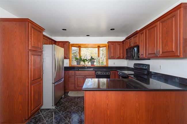 Kitchen with black appliances, granite counters, kitchen peninsula, and sink | Image 10