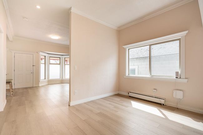 Spare room with a baseboard radiator, healthy amount of natural light, light wood-type flooring, ornamental molding, and a smoke detector | Image 5
