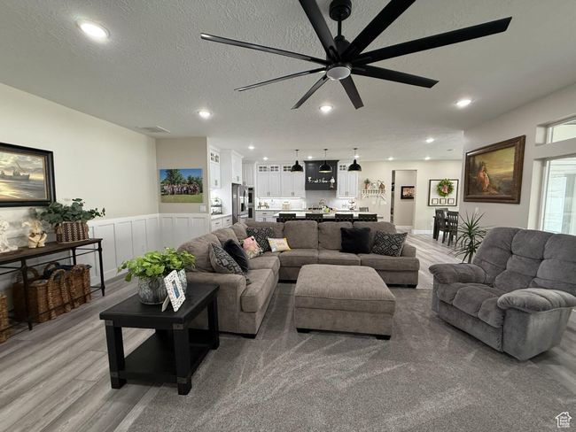 Living area with a textured ceiling, recessed lighting, a ceiling fan, light wood-type flooring, and wainscoting | Image 14