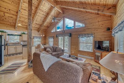 Living room featuring wood ceiling, beam ceiling, wooden walls, and light hardwood / wood-style flooring | Image 2