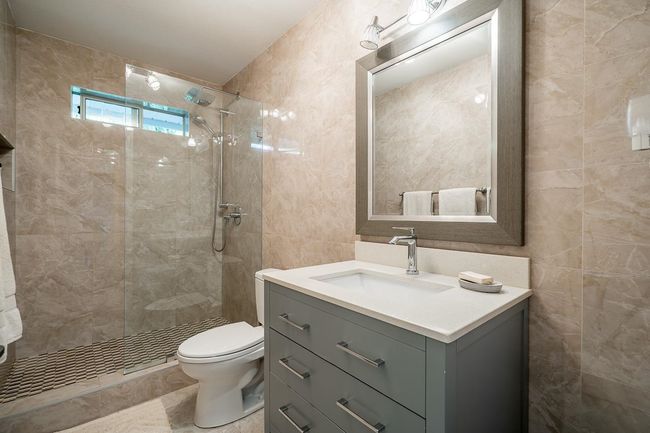 Full bathroom featuring tile walls, a tile shower, and vanity | Image 18