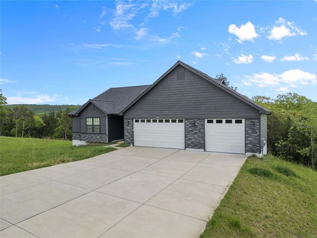View of front of house featuring driveway, a front lawn, stone siding, and a garage | Image 5