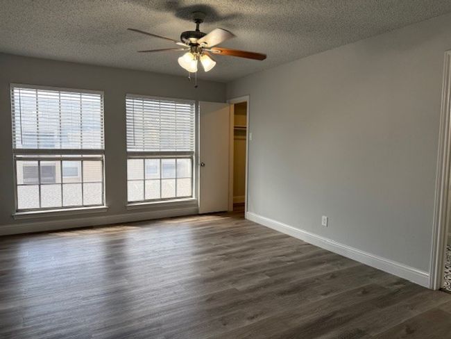 Empty room featuring ceiling fan, dark wood finished floors, and a textured ceiling | Image 5