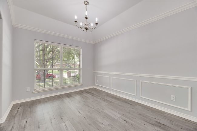 Empty room featuring a chandelier, wood finished floors, a wainscoted wall, and crown molding | Image 11
