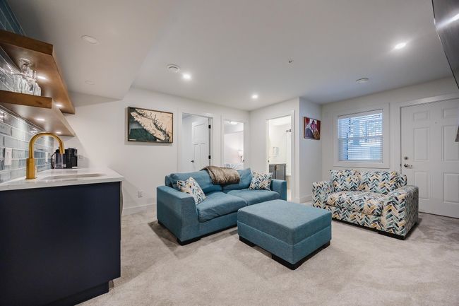 Living area with a bar, beverage cooler, a large fireplace, light colored carpet, and recessed lighting | Image 26