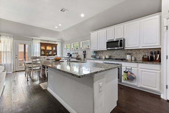 Kitchen with an island with sink, stainless steel appliances, visible vents, a sink, and tasteful backsplash | Image 10