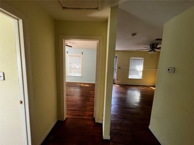 Hall with wood finished floors, baseboards, and attic access | Image 5