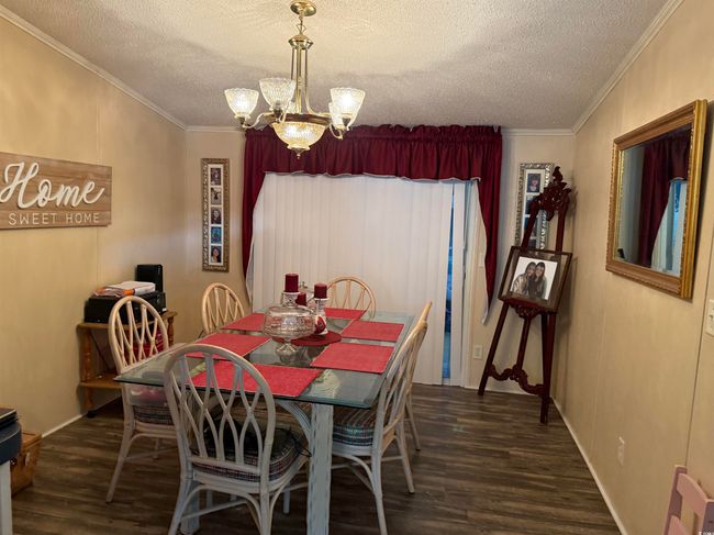 Dining room with dark wood-style floors, a chandelier, crown molding, and a textured ceiling | Image 7