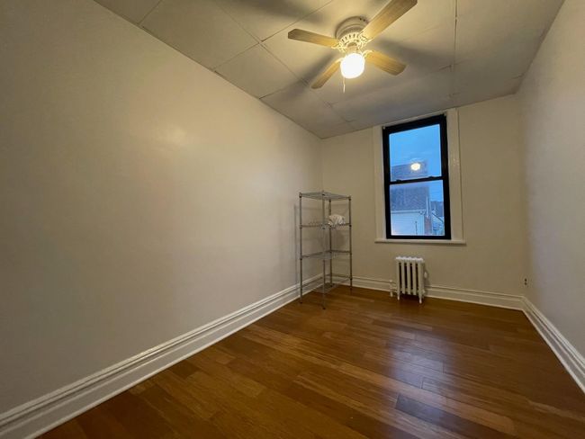 Spare room with radiator heating unit, dark wood-style floors, baseboards, and a ceiling fan | Image 6