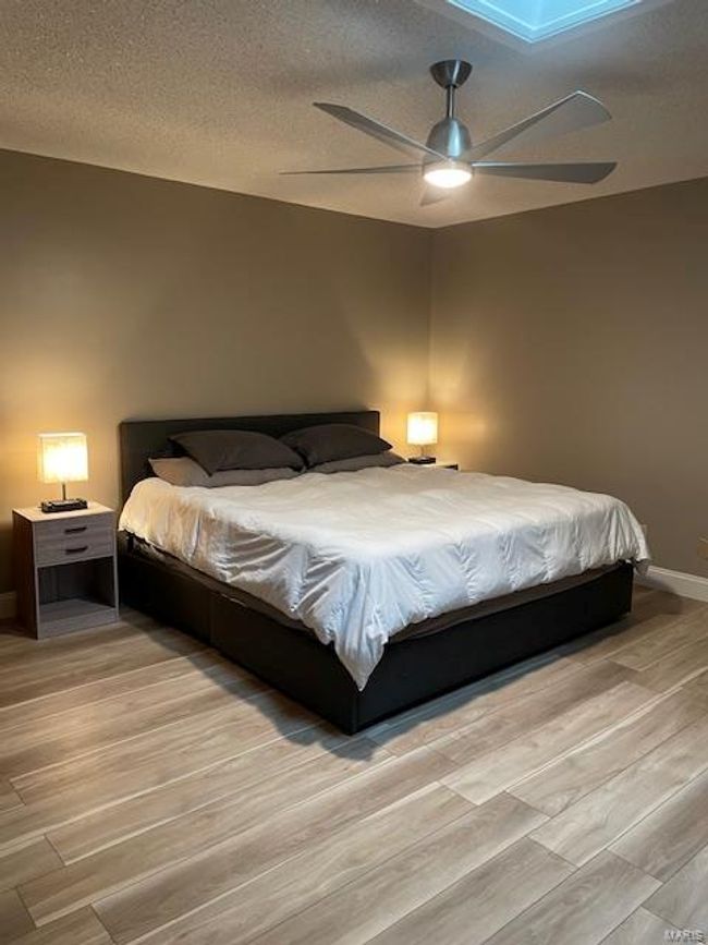 Bedroom with ceiling fan, light hardwood / wood-style flooring, and a textured ceiling | Image 6