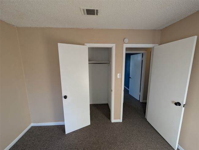 Unfurnished bedroom featuring a closet, dark colored carpet, visible vents, and baseboards | Image 27