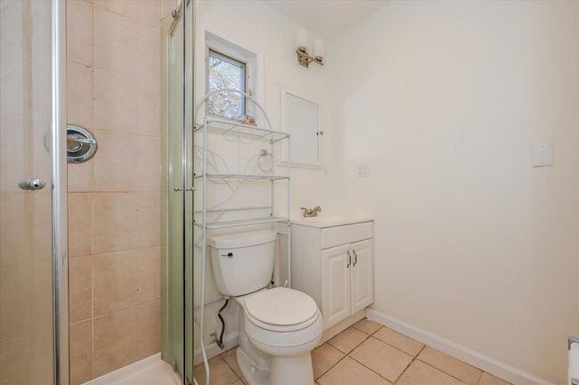 Bathroom featuring toilet, a stall shower, tile patterned floors, baseboards, and vanity | Image 14