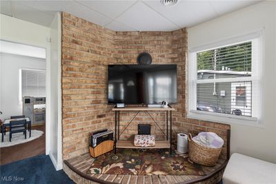 Carpeted living room with a drop ceiling and brick wall | Image 3