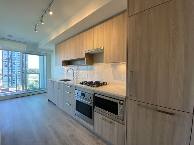 Kitchen with stainless steel appliances, rail lighting, a sink, modern cabinets, and light wood-style floors | Image 4