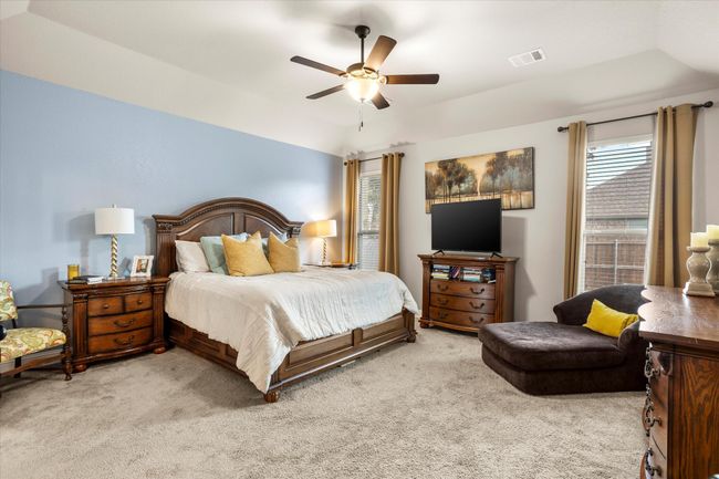Bedroom with a tray ceiling, visible vents, a ceiling fan, light carpet, and vaulted ceiling | Image 19