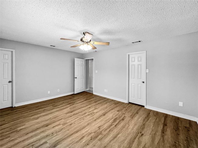 Unfurnished bedroom featuring wood finished floors, a textured ceiling, and ceiling fan | Image 14