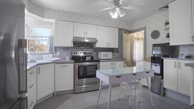 Kitchen featuring light countertops, a sink, appliances with stainless steel finishes, under cabinet range hood, and white cabinets | Image 16