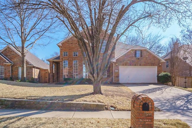 Traditional-style house featuring an attached garage, fence, concrete driveway, and brick siding | Image 27