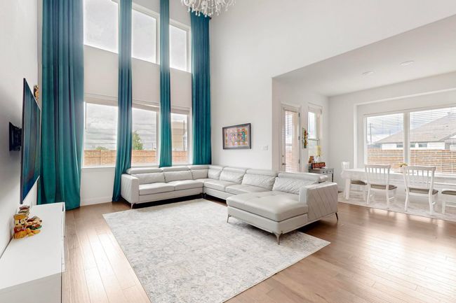 Living area featuring a notable chandelier, wood-type flooring, and a towering ceiling | Image 6