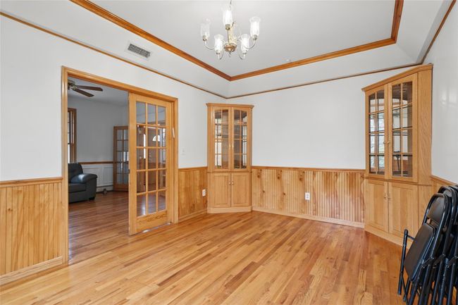 Spare room with wood finished floors, visible vents, a wainscoted wall, and french doors | Image 19