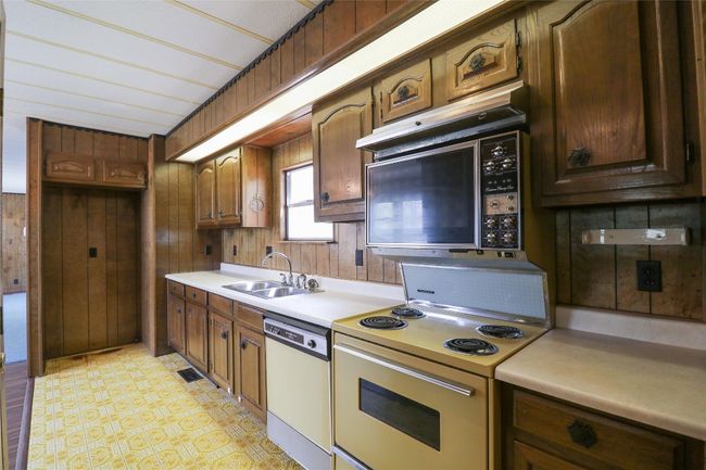 Kitchen featuring white appliances, light countertops, and wood walls | Image 6