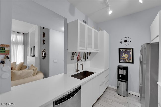 Kitchen with appliances with stainless steel finishes, light countertops, white cabinets, and glass insert cabinets | Image 13