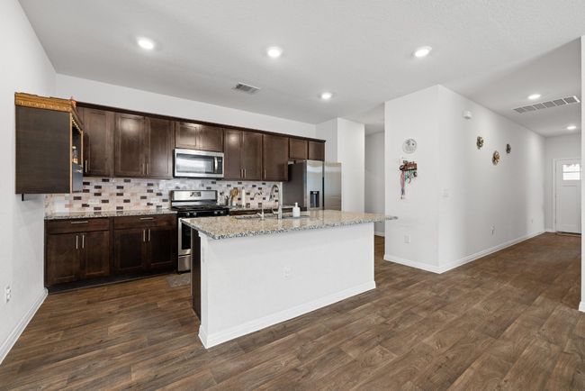 Kitchen featuring appliances with stainless steel finishes, a sink, dark wood-type flooring, dark brown cabinets, and recessed lighting | Image 10