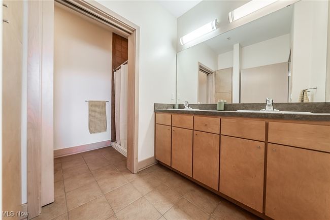 Full bathroom featuring double vanity, a walk-in shower, storage, and tile flooring. | Image 24