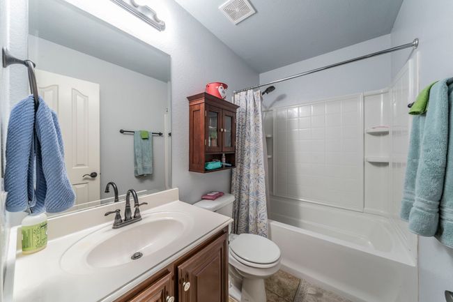 Full bath featuring toilet, vanity, shower / bath combo with shower curtain, and tile patterned flooring | Image 18