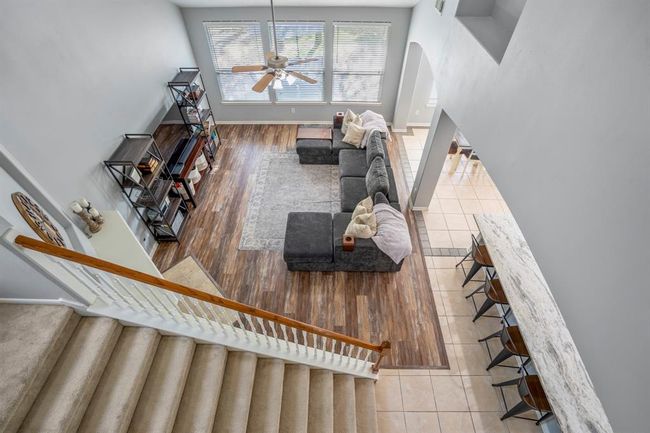 From the upstairs game room, look over the railing for a dramatic view of the living room below, framed by grand vaulted ceilings and large windows. This elevated vantage point also reveals a subtle tile inlay outlining the breakfast area—a stylish detail that defines the space while preserving the home's open-concept flow. | Image 22