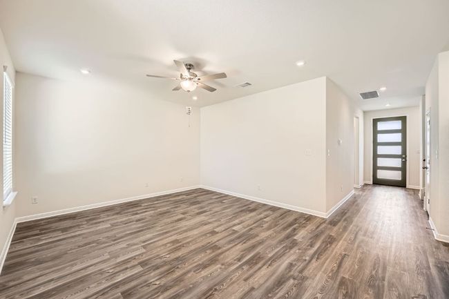 Empty room with a wealth of natural light, visible vents, ceiling fan, and dark wood-style flooring | Image 5