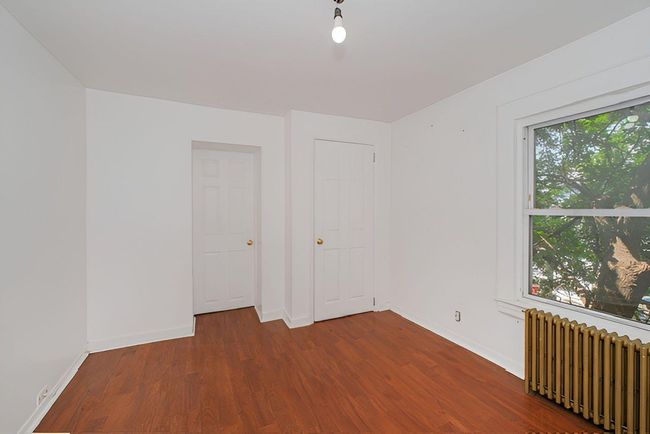 Spare room with radiator heating unit and wood finished floors | Image 8