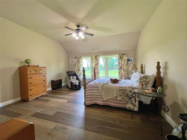 Bedroom featuring vaulted ceiling, wood finished floors, baseboards, a ceiling fan, and access to exterior | Image 19
