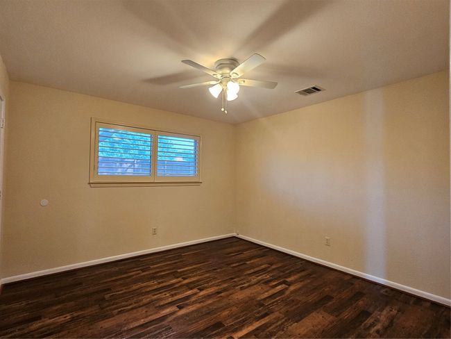 Empty room with dark wood finished floors and ceiling fan | Image 8