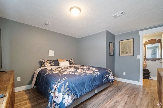 Bedroom with baseboards, visible vents, wood finished floors, and a textured ceiling | Image 18