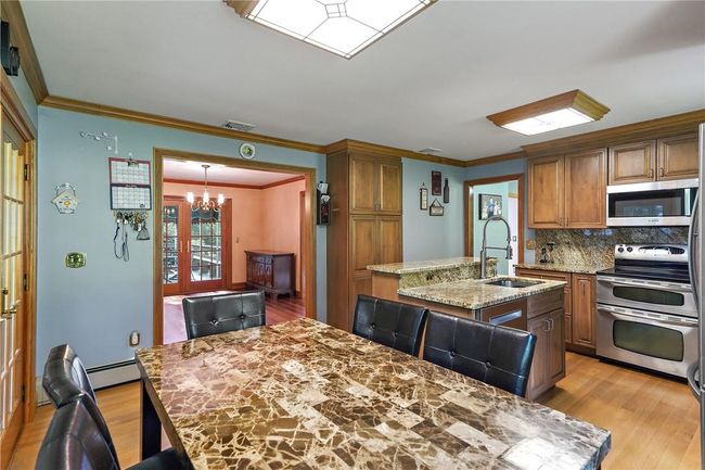 Kitchen featuring sink, light wood-type flooring, stainless steel appliances, and a center island with sink | Image 9