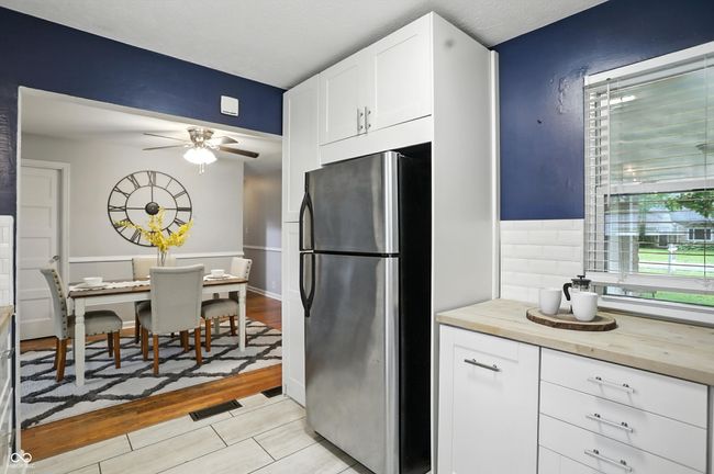 kitchen featuring freestanding refrigerator, ceiling fan, white cabinets, wood counters, and light tile patterned flooring | Image 8