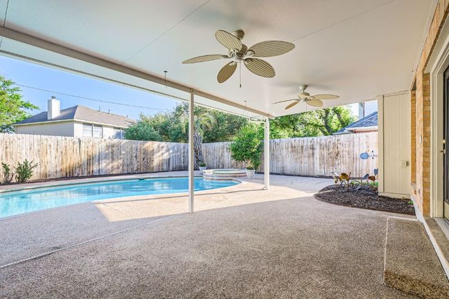 View of swimming pool with ceiling fan, a patio, a fenced backyard, and a pool with connected hot tub | Image 36