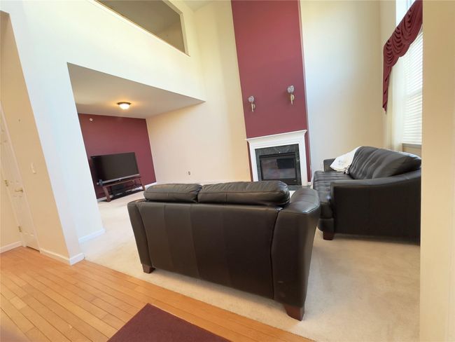 Living area featuring a high ceiling, light wood-type flooring, a high end fireplace, and baseboards | Image 10