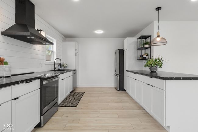 kitchen featuring exhaust hood, a sink, light wood-style floors, white cabinetry, and stainless steel appliances | Image 33